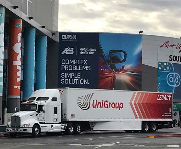 large crated cargo being craned onto drop bed truck